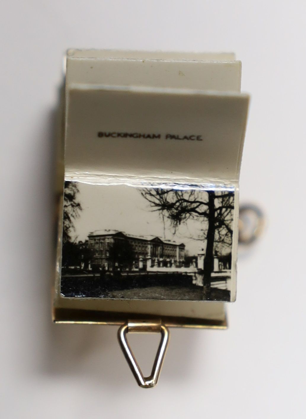 An enamelled 9ct gold photograph album charms with views and crest of London, 1.5cm gross 3.1 grams